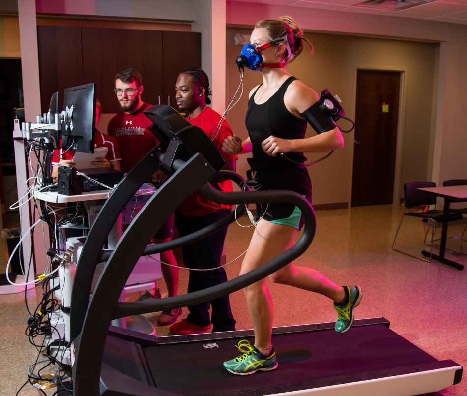 student running on treadmill while fellow students monitor her breathing